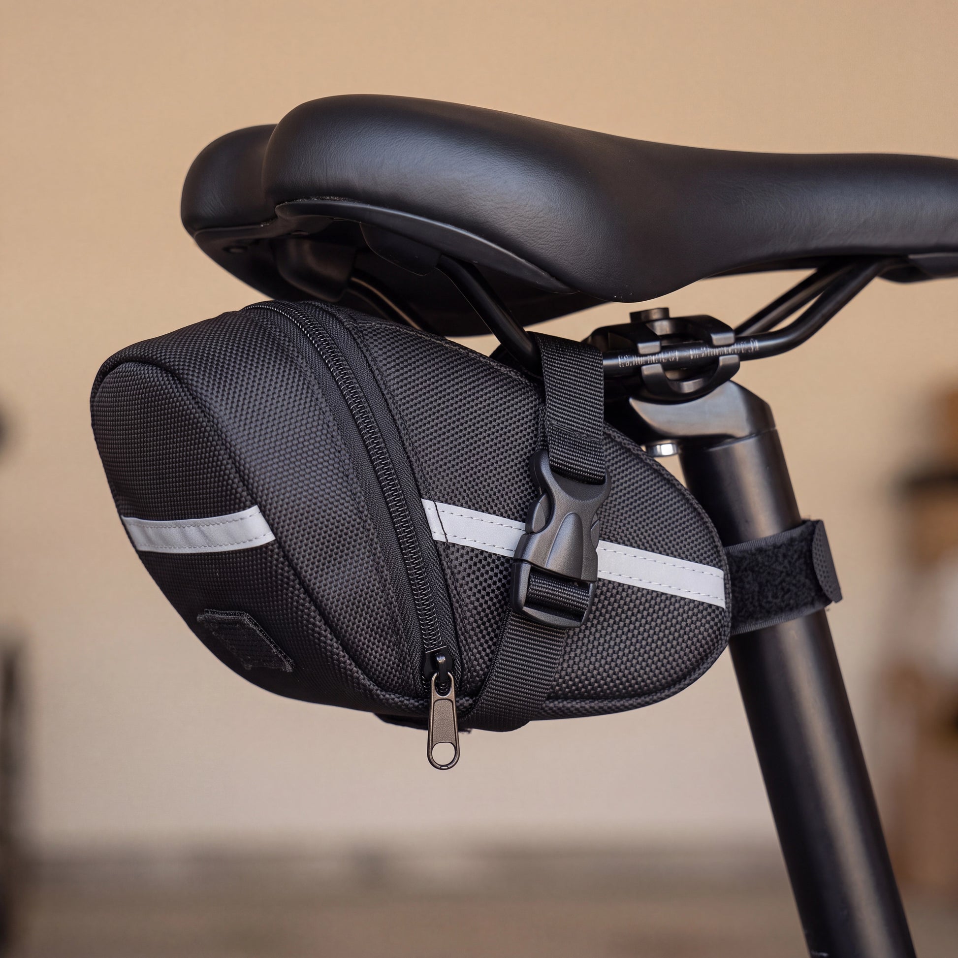 Fixation sans outil de la sacoche vélo sous-selle nylon : sangle sur les rails et Velcro sur la tige de selle